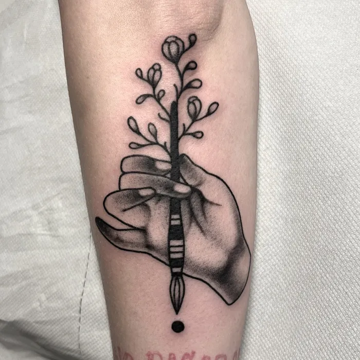 Tatouage d'une main tenant un pinceau fleuri
